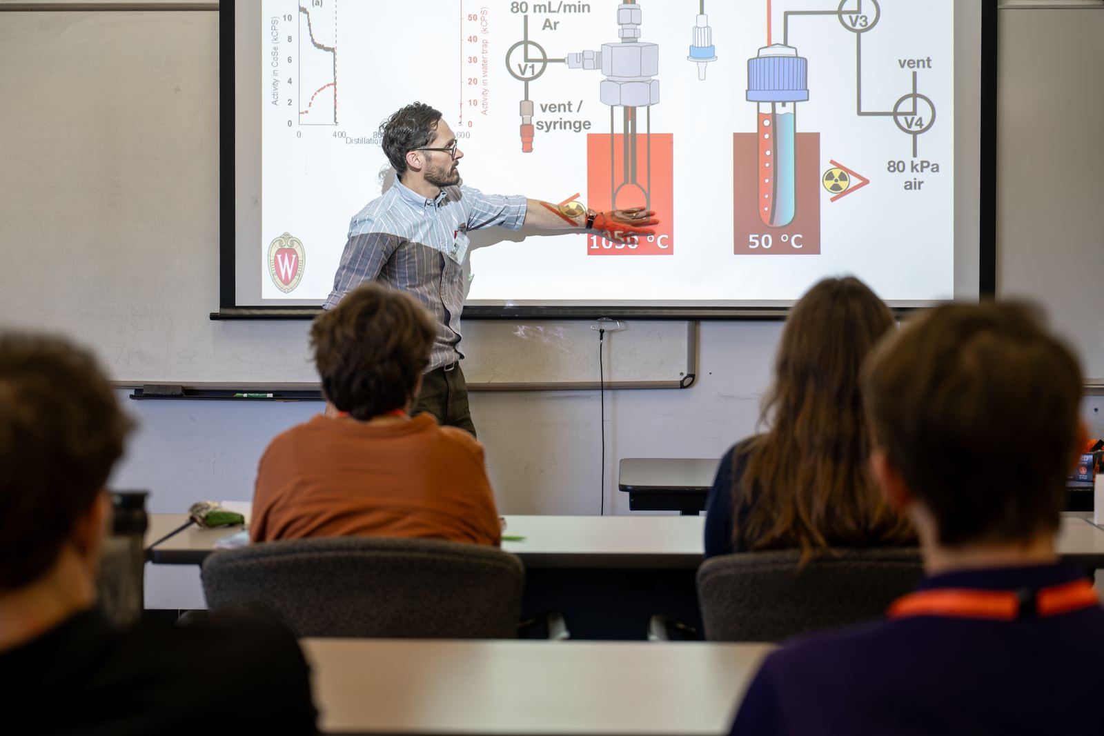 An instructor explains a radiochemistry apparatus diagram to NCSS students in a classroom at Brookhaven National Laboratory