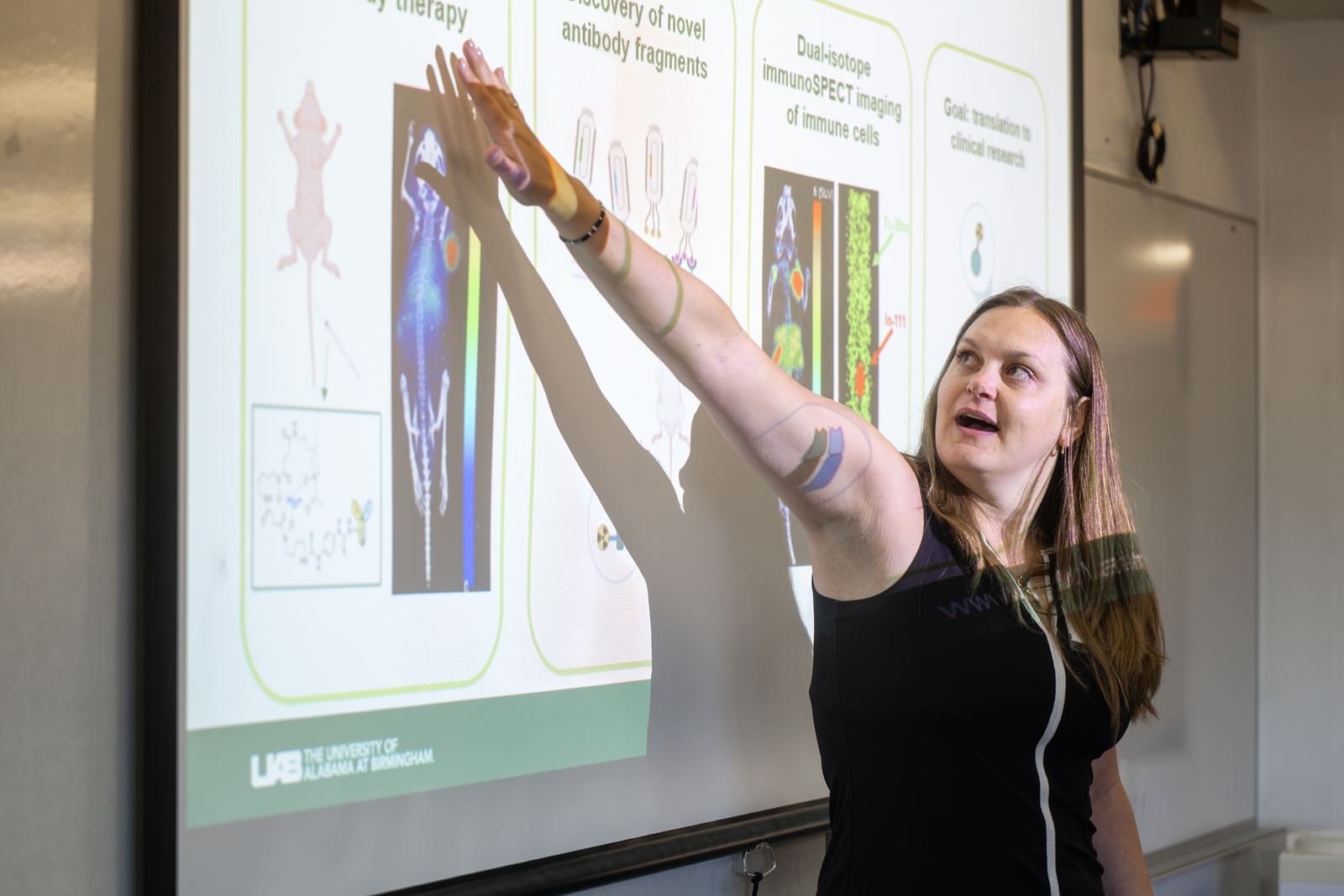 A guest lecturer points to slides on antibody imaging during an NCSS lecture