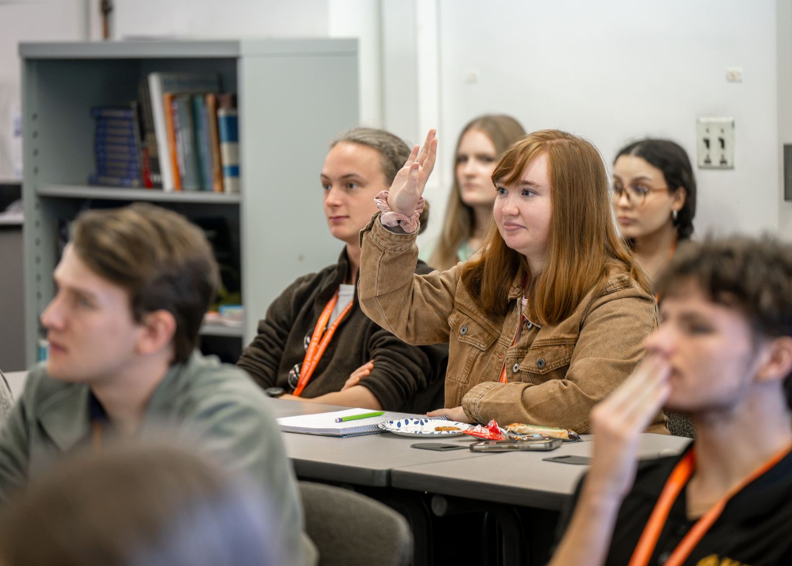 An NCSS student raises a hand to ask a question during a lecture