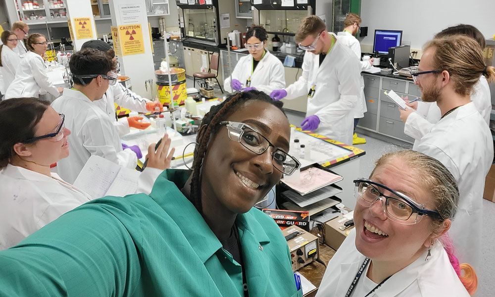 Smiling NCSS students and instructors take a selfie in a radiochemistry lab